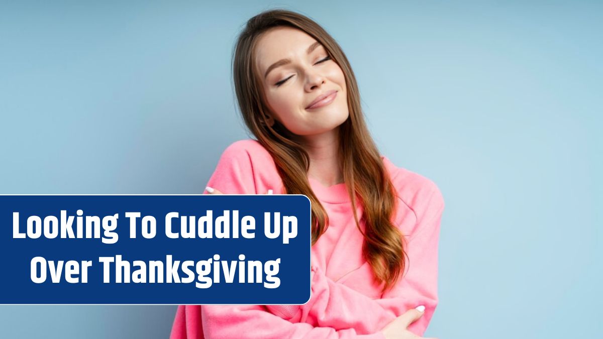 Portrait of cute woman hugging herself with closed eyes isolated on blue background.