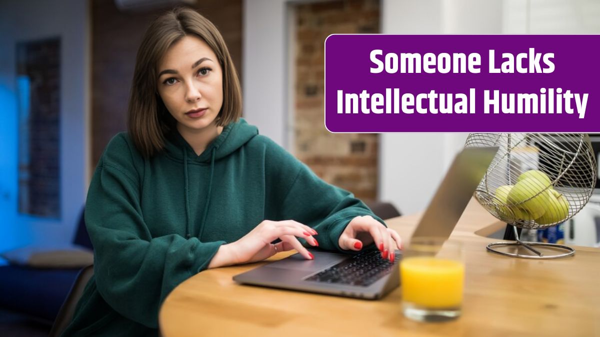 Surprised brunette woman is working on her laptop on the kitchen table drinking orange juice.