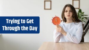 A young Caucasian lady sits at home at a desk and holds a watch in her hands It is 12 o'clock in the afternoon for lunch Rest and break during the working day banner.